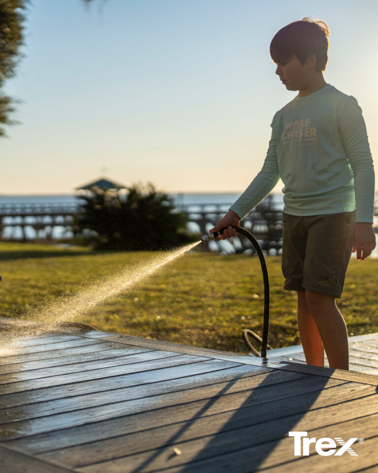photo of a man cleaning his trex deck with a hose, showing how easy maintenance and cleaning is